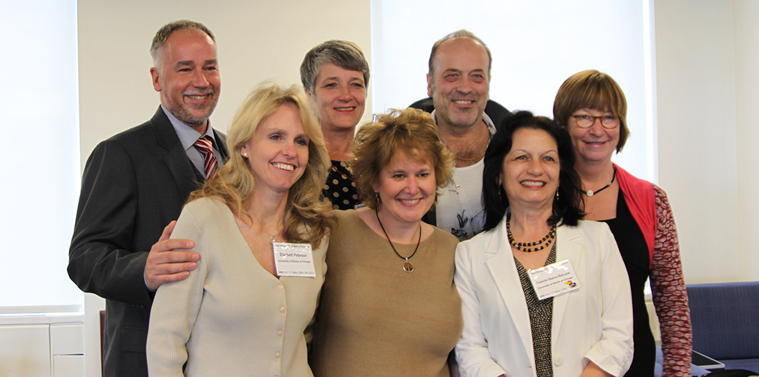 A group of 7 people smiling and standing